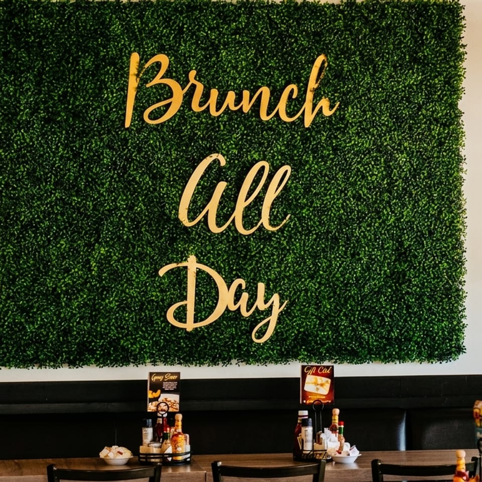 A green wall with "Brunch All Day" in gold lettering, above restaurant tables and booths.